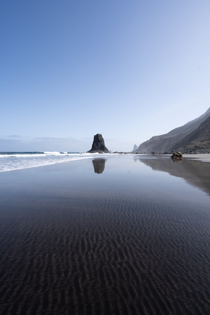 Foto vertical da costa rochosa do mar com os traços naturais na água transparente