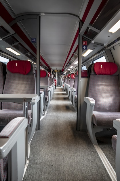 Foto vertical das filas de assentos vermelhos e cinza dentro de um trem vazio