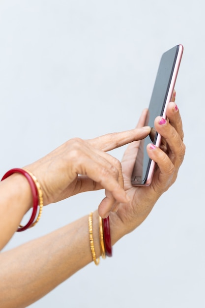 Foto vertical das mãos enrugadas de uma mulher usando um smartphone moderno