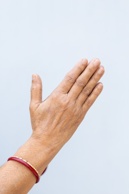 Foto vertical das mãos orando de uma pessoa em um fundo cinza