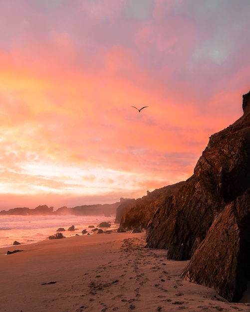 Foto vertical das montanhas na praia durante o pôr do sol