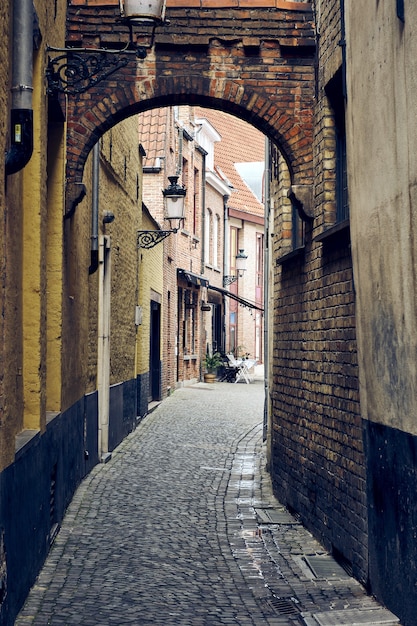 Foto vertical das ruas estreitas de Bruges, na Bélgica, com paredes de tijolos antigos