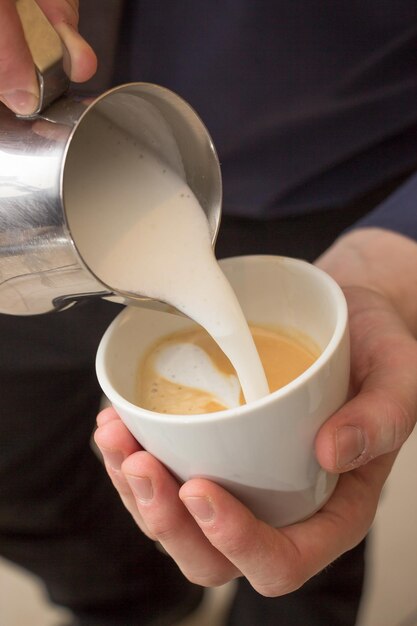 Foto vertical de alto ângulo de um homem fazendo uma xícara de cappuccino