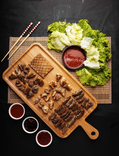 Foto vertical de alto ângulo de uma bandeja de carne frita, batatas, molho e vegetais