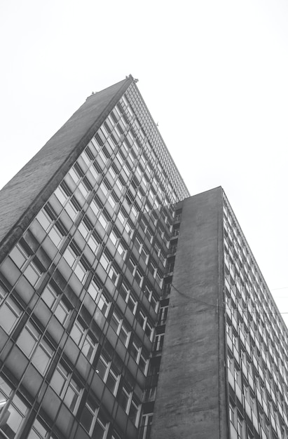 Foto vertical de baixo ângulo em tons de cinza de um edifício residencial durante o dia