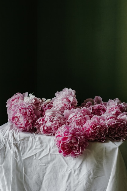 Foto grátis foto vertical de belas peônias rosa pastel desabrochando em uma mesa