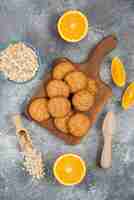Foto grátis foto vertical de biscoitos caseiros com aveia e fatias de laranja sobre a mesa cinza.