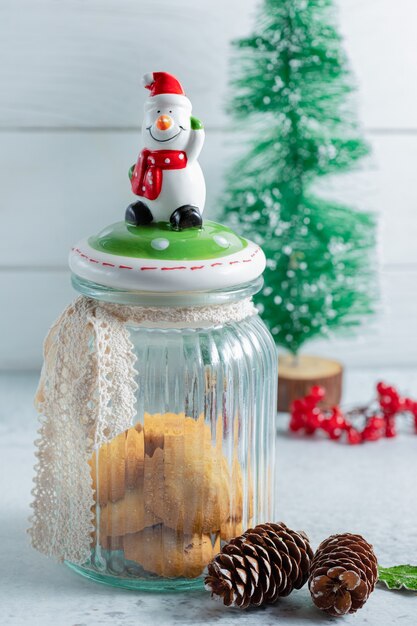 Foto vertical de biscoitos de Natal cremosos em uma jarra sobre uma superfície cinza com decorações de Natal.