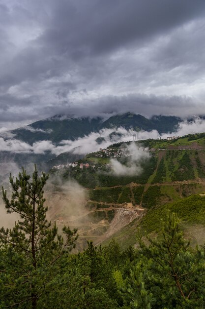 Foto vertical de campos e montanhas cobertos de grama sob um lindo céu nublado