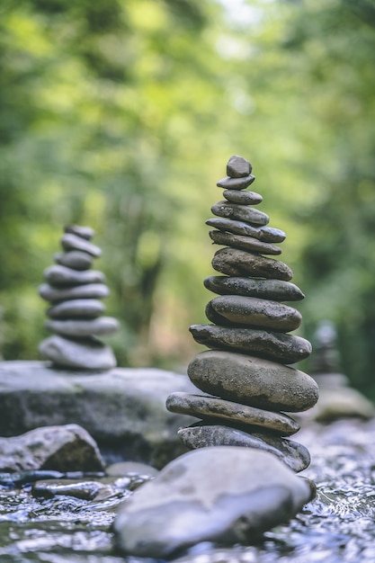 Foto vertical de duas pirâmides de pedra equilibradas na água de um rio