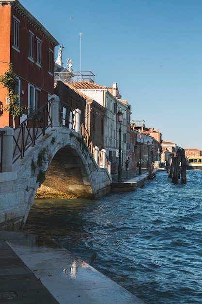 Foto vertical de edifícios e uma ponte sobre a água nos canais de Veneza na Itália