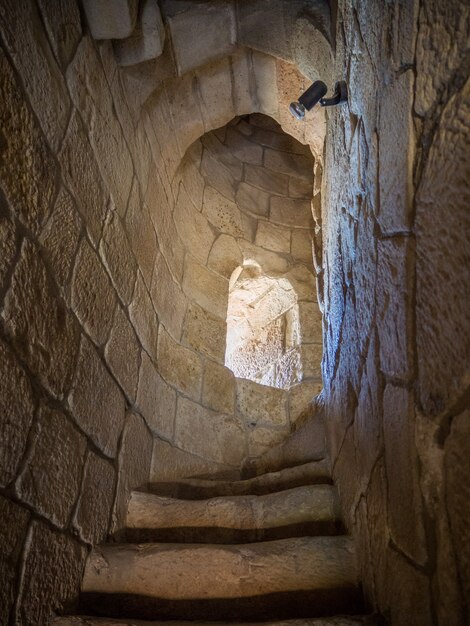 Foto vertical de escadas estreitas dentro de uma torre de pedra com uma pequena janela