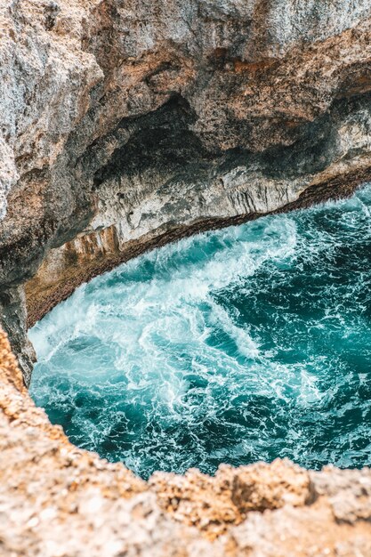 Foto vertical de fortes ondas do mar batendo no penhasco