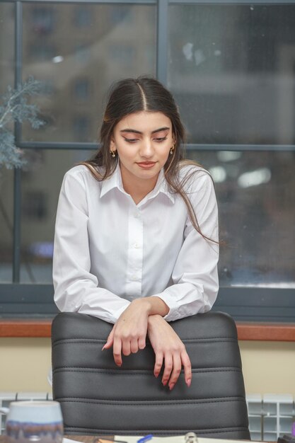 Foto vertical de garota pensativa no escritório