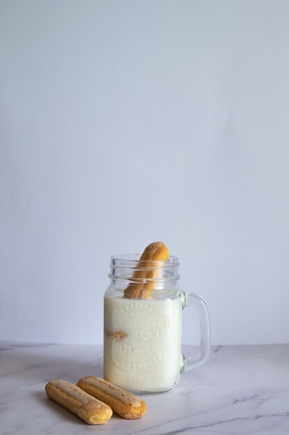 Foto vertical de milk-shake caseiro com biscoitos na parede branca
