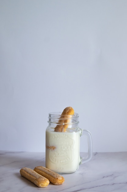 Foto vertical de milk-shake caseiro com biscoitos na parede branca