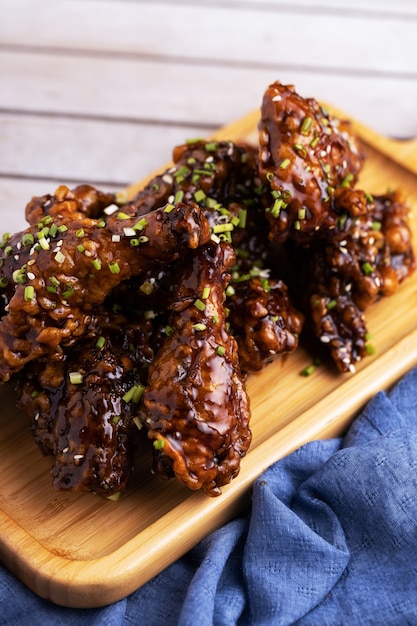 Foto vertical de pedaços de frango assado em um prato de madeira e um pouco de tempero