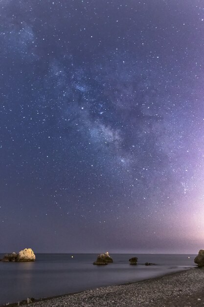 Foto vertical de pedras na praia Torre de la Sal, na Espanha, em uma bela noite