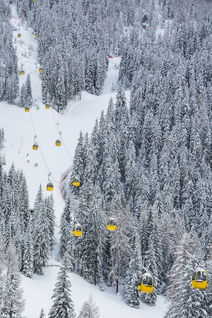 Foto vertical de teleféricos amarelos na montanha durante o inverno