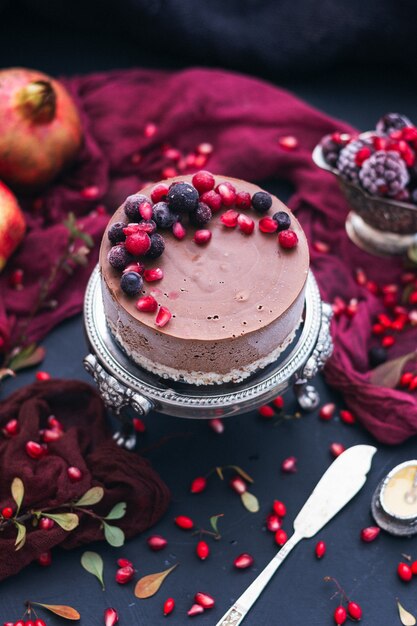 Foto vertical de um bolo de chocolate com frutas frescas e sementes de romã