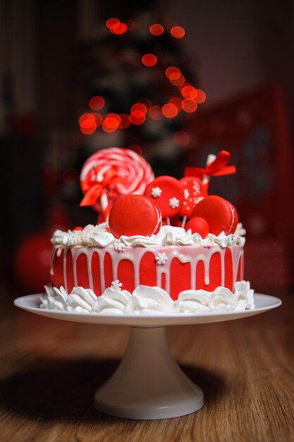 Foto vertical de um bolo de Natal com decorações vermelhas sobre fundo desfocado