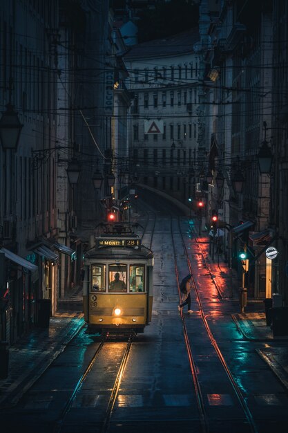 Foto vertical de um bonde passando pelos edifícios de uma cidade durante a noite