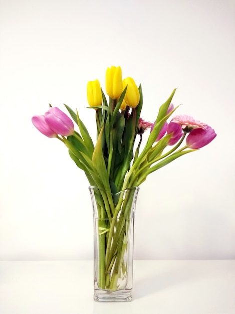 Foto vertical de um buquê de tulipa em um vaso na mesa sob as luzes