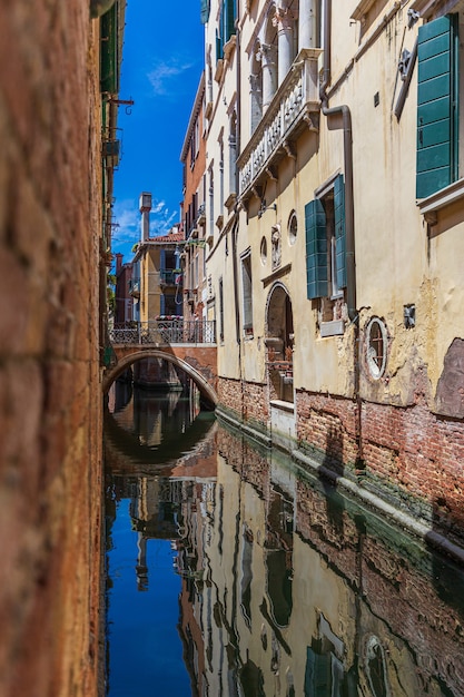 Foto vertical de um canal estreito em Veneza, Itália, durante o dia