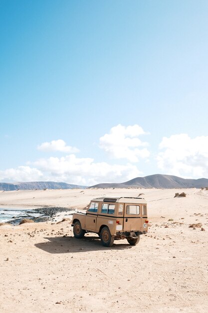 Foto vertical de um carro off-road parado em um deserto