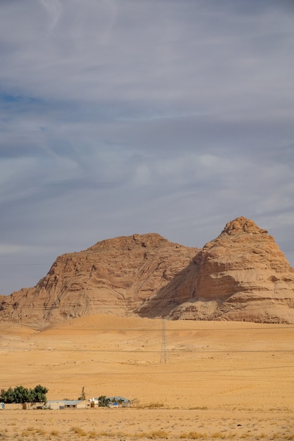 Foto vertical de um grande penhasco em um deserto sob um céu nublado