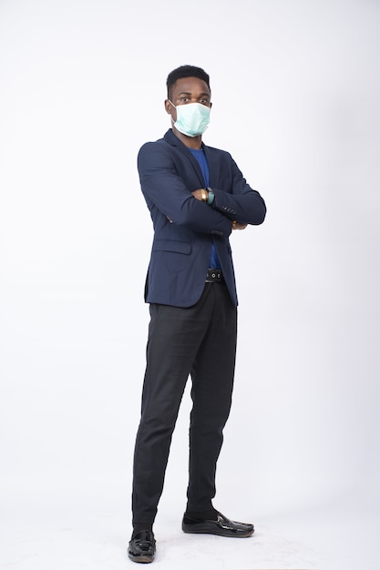 Foto vertical de um jovem negro vestindo um terno e uma máscara facial em pé com confiança