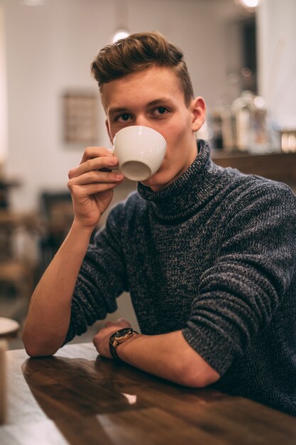 Foto vertical de um jovem tomando café no café