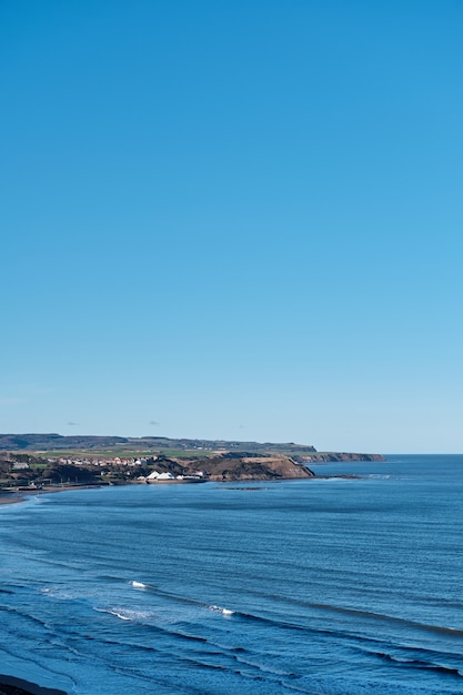 Foto vertical de um mar azul e um céu claro durante o dia