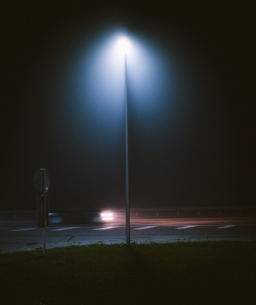 Foto vertical de um poste de luz na rua, capturada durante a noite
