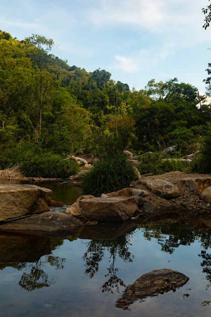 Foto vertical de um rio com pedras no penhasco das cachoeiras de ba ho, no vietnã