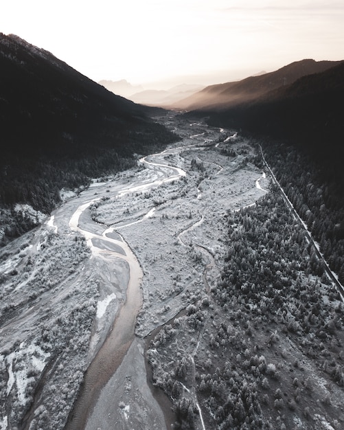 Foto vertical de um rio meio congelado fluindo pelas montanhas