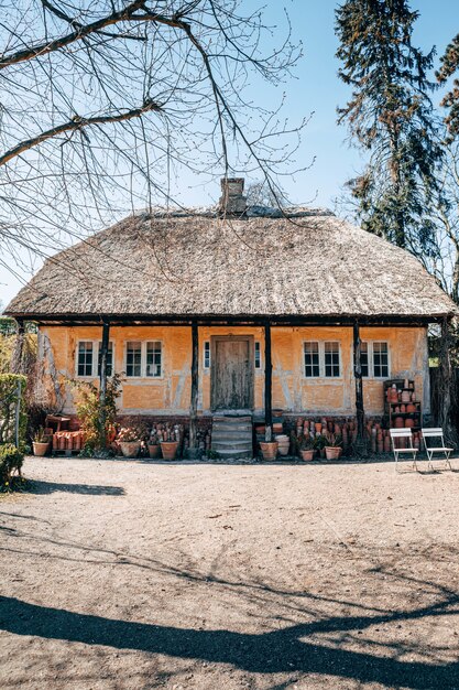 Foto vertical de uma bela casa de aldeia entre as árvores capturada em um dia ensolarado