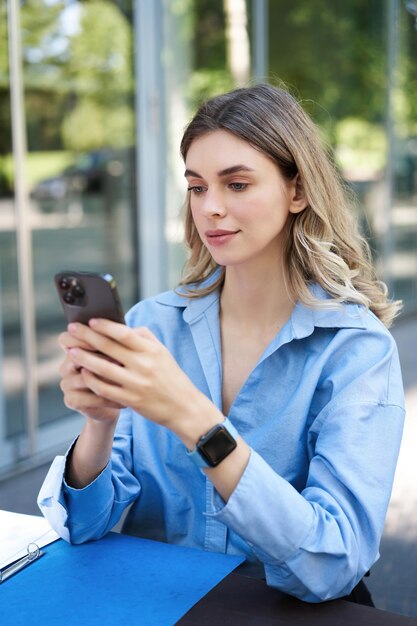 Foto vertical de uma empresária de sucesso sentada ao ar livre no parque trabalhando em seu projeto usando mobi