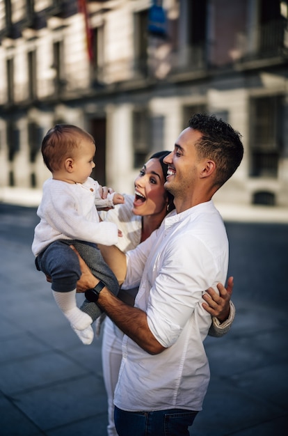 Foto grátis foto vertical de uma família caucasiana feliz segurando seu filho bebê