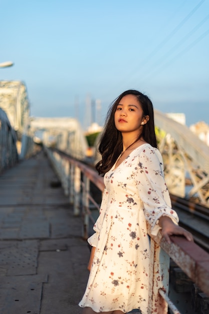 Foto vertical de uma garota vietnamita em uma ponte velha