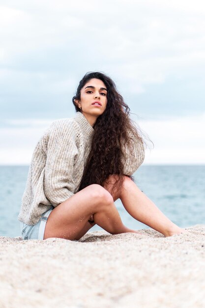 Foto vertical de uma jovem mulher sentada em uma praia