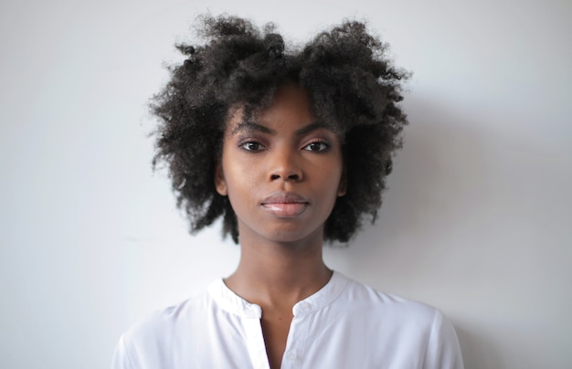 Foto vertical de uma linda mulher afro-americana em pé perto de uma parede