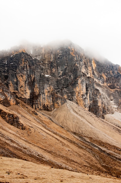 Foto vertical de uma montanha sob as nuvens no Himalaia, no Butão