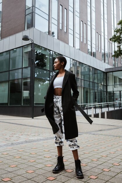 Foto vertical de uma mulher afro-americana vestindo um casaco e posando na rua