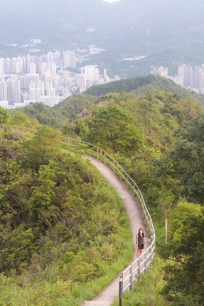 Foto vertical de uma mulher caminhando em um caminho estreito cercado por árvores e vegetação