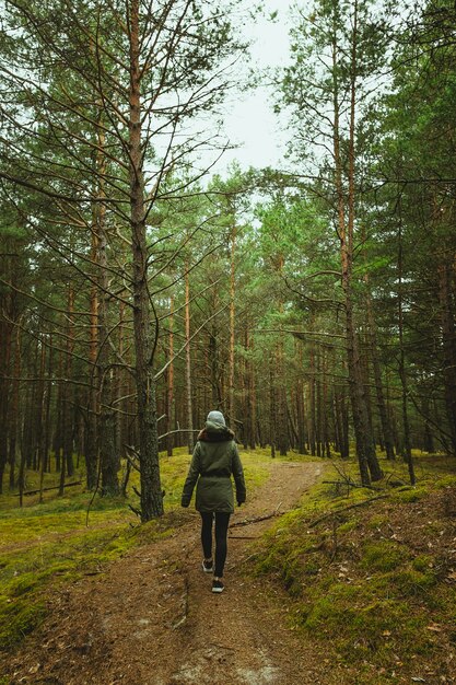 Foto vertical de uma mulher caminhando pela floresta