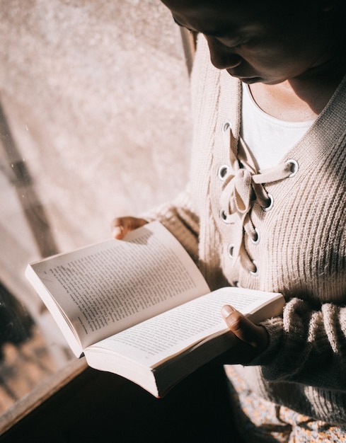 Foto vertical de uma mulher lendo um livro