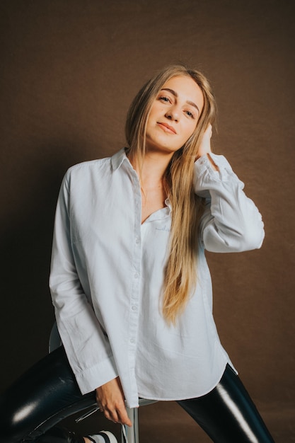 Foto vertical de uma mulher loira atraente posando sentado em uma banqueta