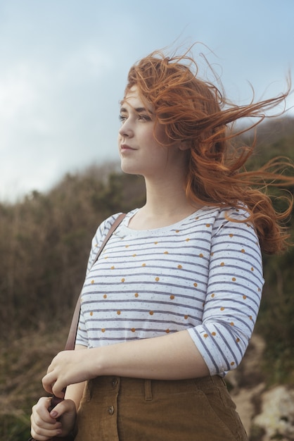 Foto vertical de uma mulher sorridente com as árvores ao fundo