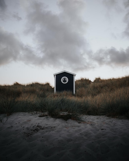 Foto vertical de uma pequena cabana em uma praia sob um céu nublado em Skanor Suécia